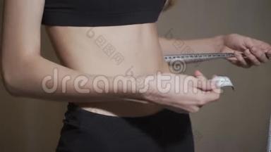 腰部测量。 一个女人用厘米胶带测量她的腰部。